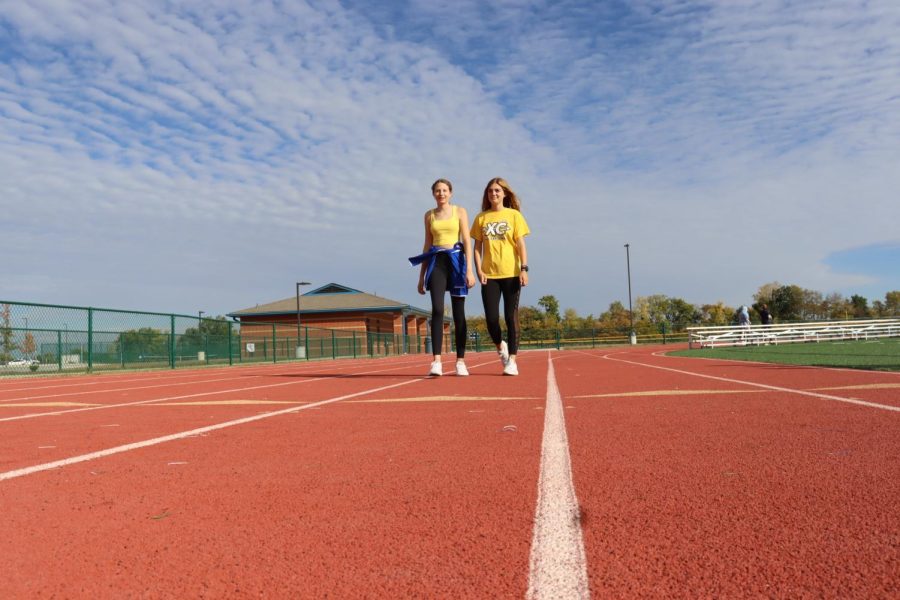 Olivia Prine (26) and Eliza Moore (26) walk the track in their freshman color: yellow. We would have rather been blue, but it was fine, Moore said. Im excited for my volleyball tournament, which is Saturday and then Im going to the dance.