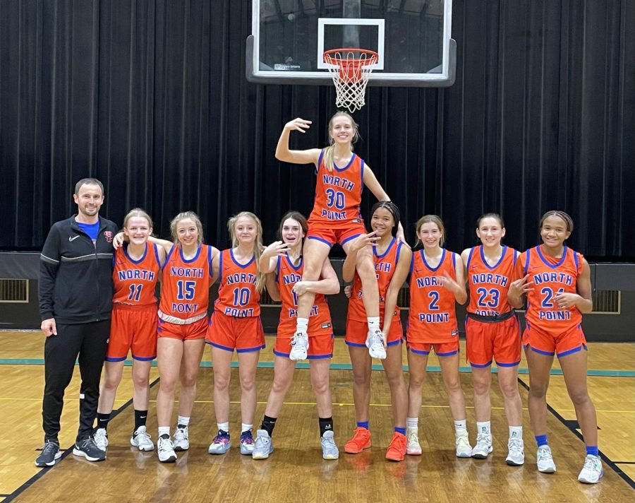 The team holds up Emma Wilke (25) after their first varsity win.