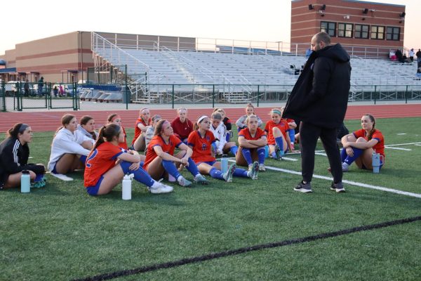 Girls varsity soccer coach giving a pre-game pep talk at the Grizzly field.