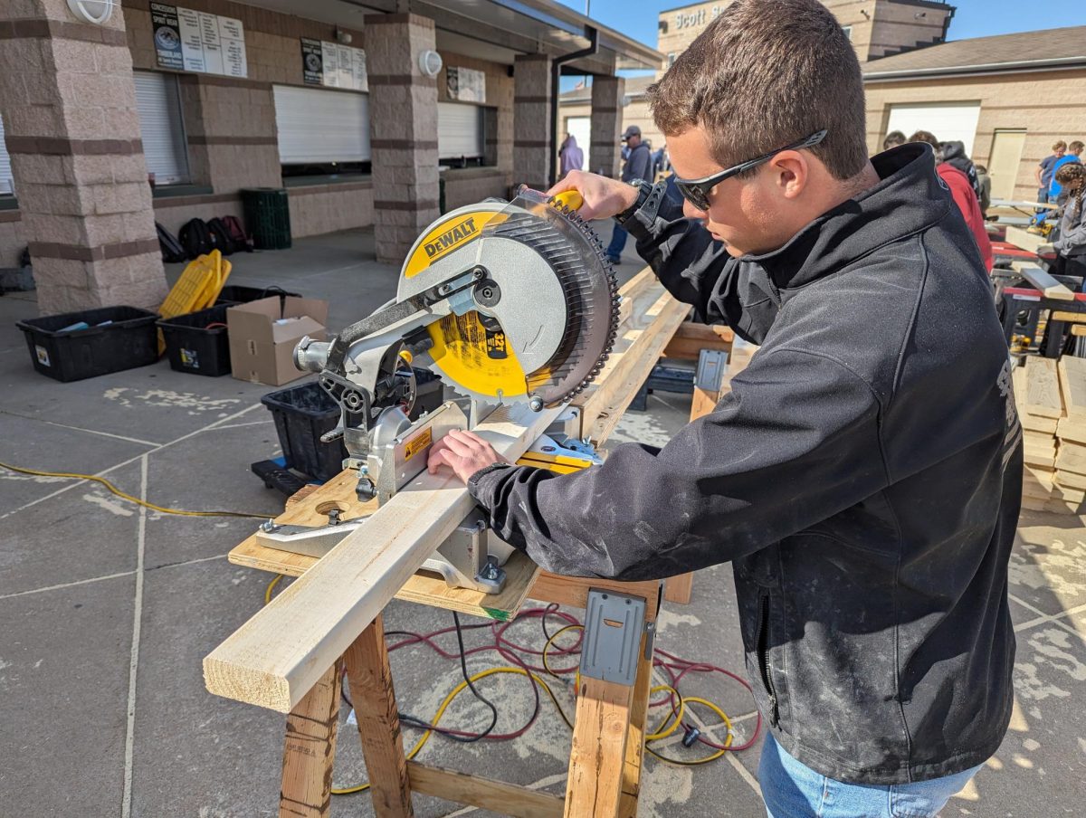 Kyler Bristow (‘26) uses a buzz saw to cut the bed frames to make sure they are all the same length.