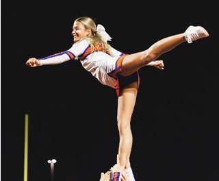 Joie Dreisewerd ('25) is held confidently by her cheer squad during the football game.